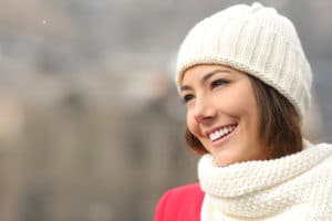 A woman in a hat and scarf smiling 