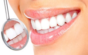Woman with white teeth smiling in a dental mirror.