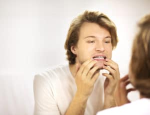 young man looking in the mirror at his teeth