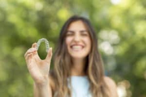 Beautiful smiling Turkish woman is holding an invisalign bracer