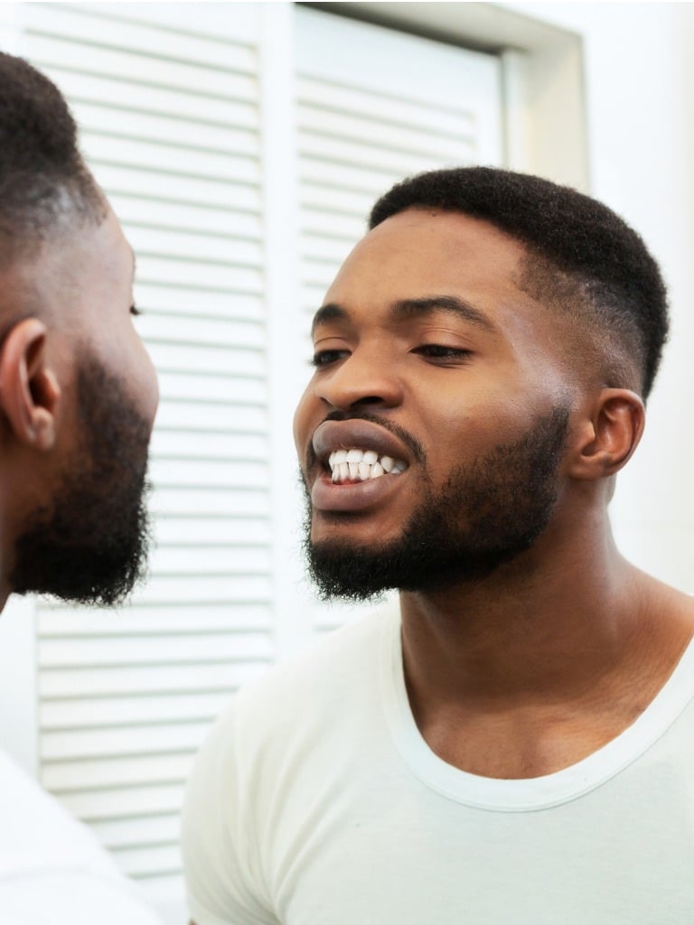 young black man looking in mirror at his teeth in bathroom picture id1182649295