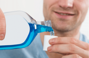 Closeup of mid adult man pouring bottle of mouthwash into cap