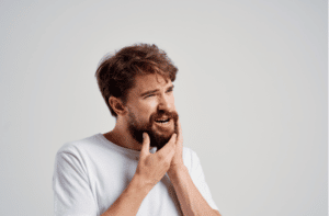 man touches his beard with his hand jaw toothache