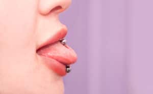 Cosmetic procedure for piercing the tongue with a needle by a beautician.