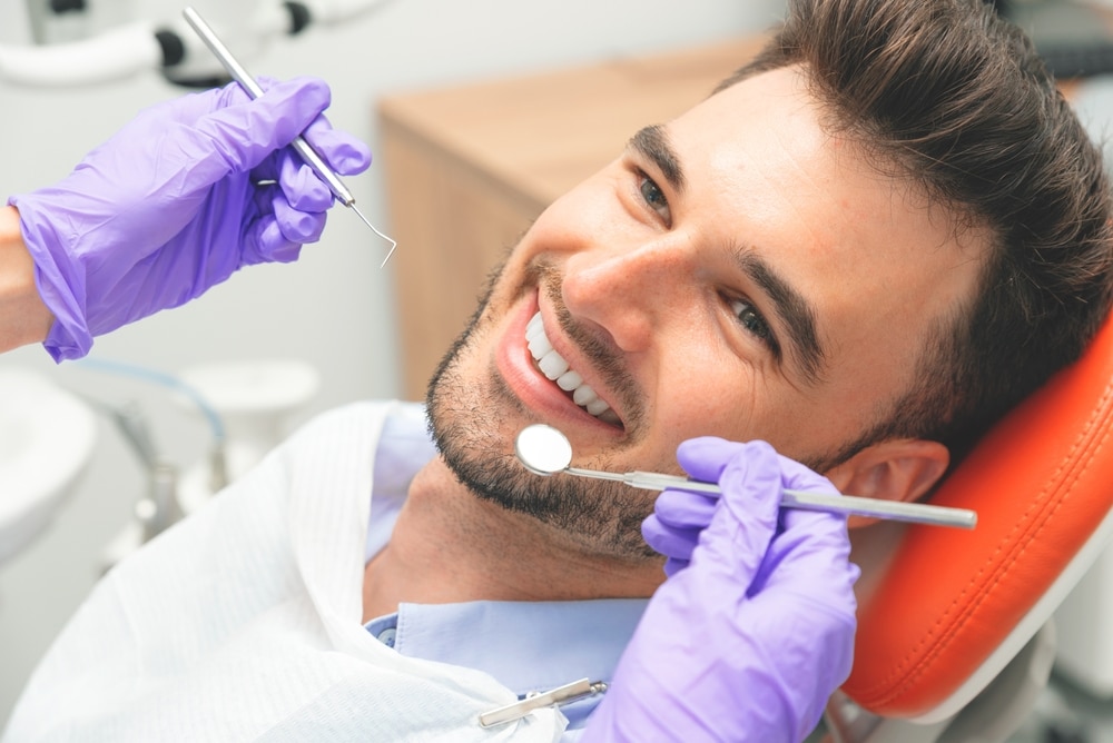 Man chats with a hygienist during a routine dental cleaning.