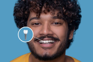 Man in front of yellow wall feels pleased with his dental implant results.